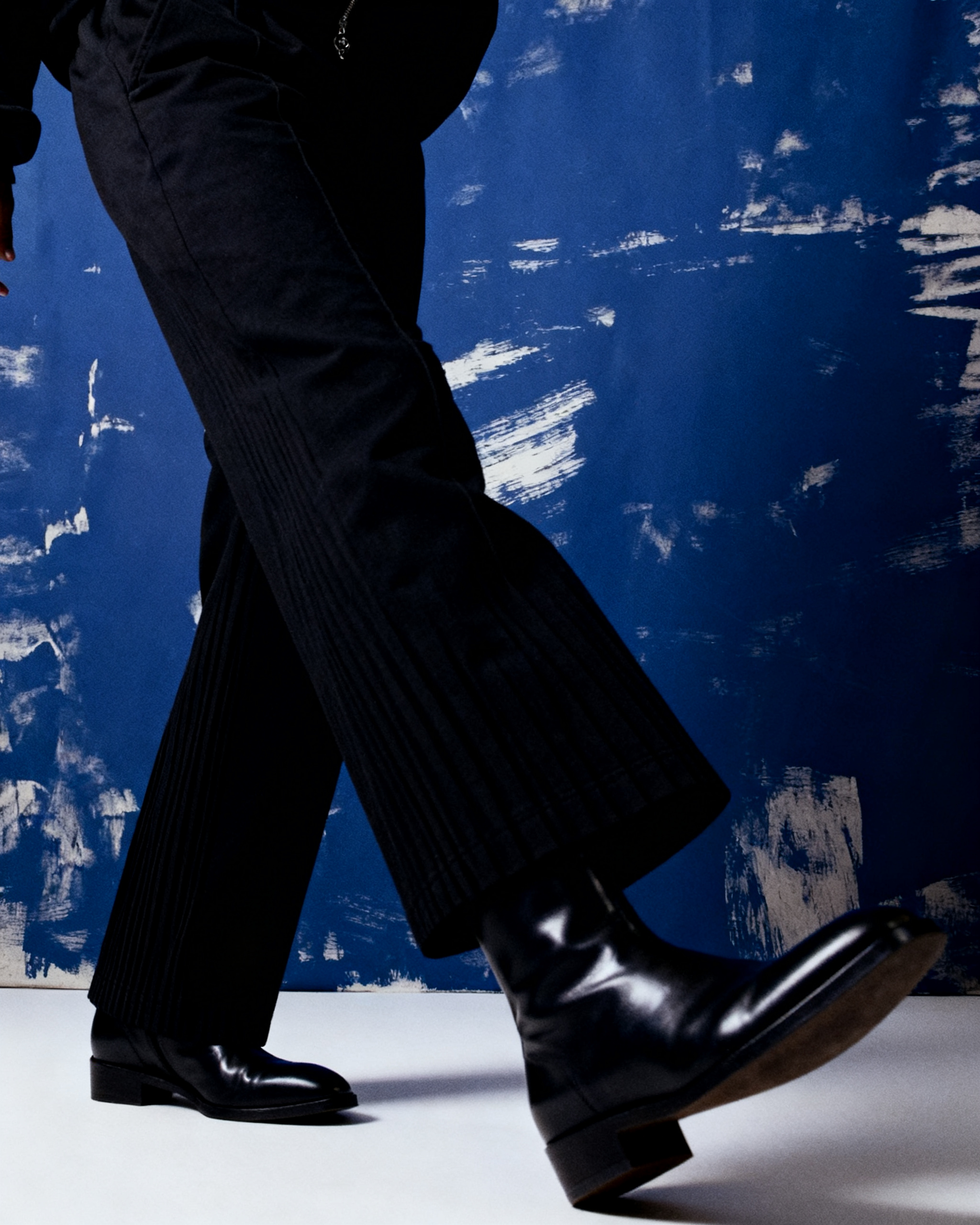 Pintuck trousers and leather boots against the cobalt backdrop